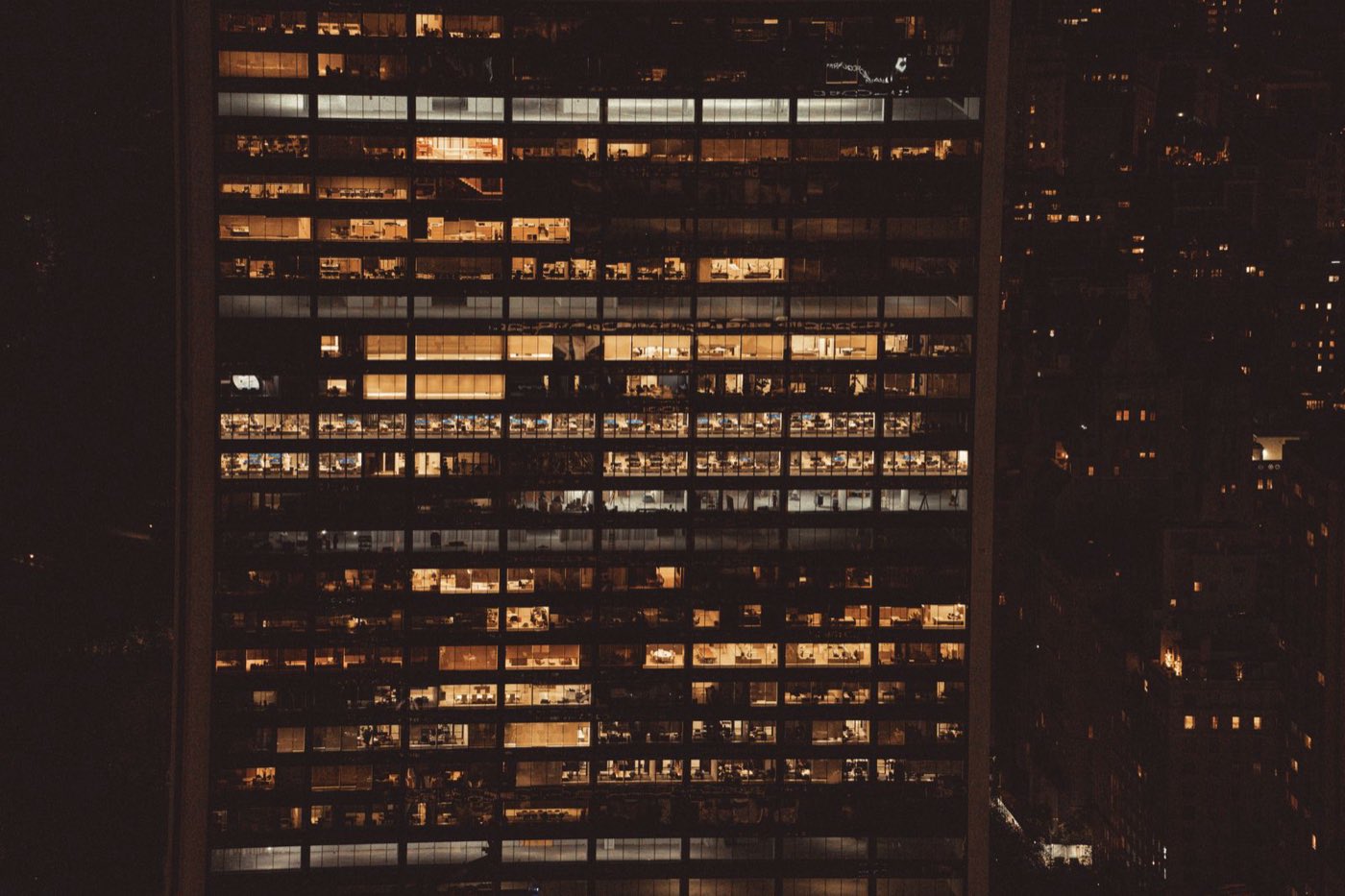 A high-rise office building at night with rows of lit windows